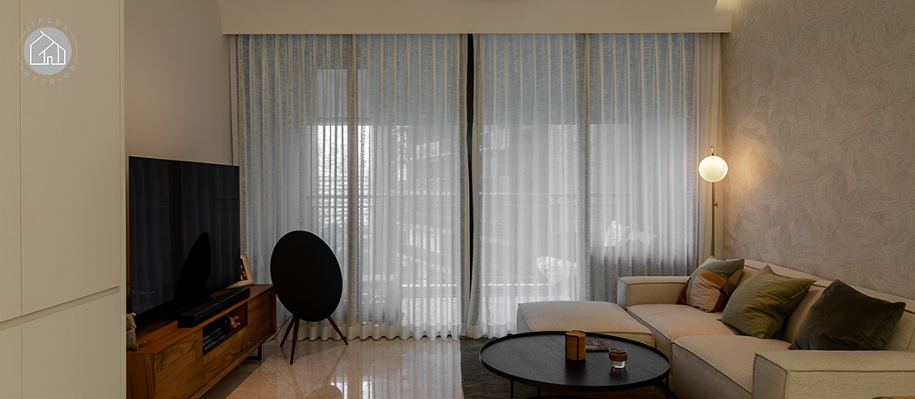 Minimalist living room with sofa, TV, and sheer curtains.