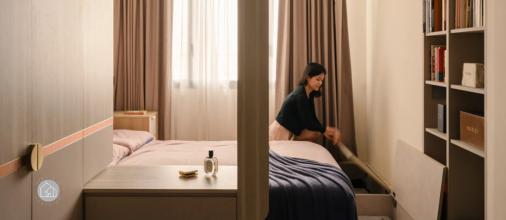 Woman using built-in storage solutions in a condominium bedroom.