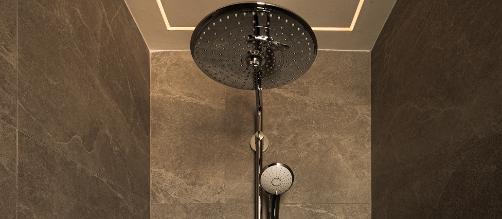 Luxury shower area featuring rainfall head and stone textures.